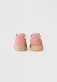 Pink suede sneakers with a beige rubber sole, featuring a textured fabric tongue and subtle branding on the heel. Rear view displayed.