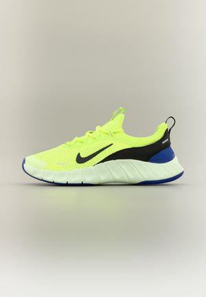 Neon-gelber und schwarzer Nike-Laufschuh mit dicker weißer Sohle und blauen Fersendetails, seitlich auf neutralem Hintergrund dargestellt.
