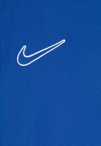 Tejido atlético azul con un logo bordado blanco de Nike swoosh, textura lisa con un ligero estiramiento y un diseño limpio.