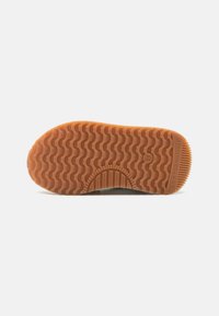 Bruine rubberen zool met een golfpatroon, geribbelde randen en merkdetails. Geweven voor verbeterde grip en tractie.