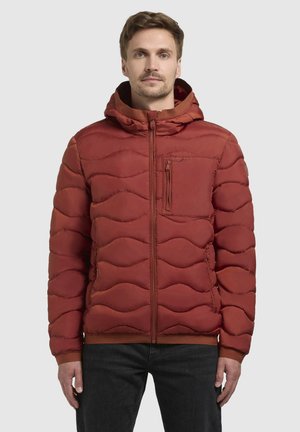 Vadderad röd jacka med en vågig quiltad design, frontzip, huva och en ficka på bröstet. Har elastiska ärmslut och nederkant.