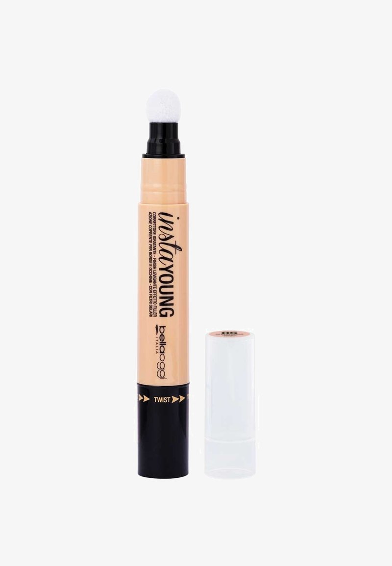 Correttore in penna beige con un applicatore rotondo e morbido. Base nera elegante con accenti dorati e nome del prodotto in carattere grassetto.