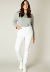 Grijze langemouwen top gecombineerd met hooggewaist witte jeans en witte sneakers. Zachte stof met een relaxte pasvorm en rechte pijp.