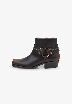 Black leather ankle boot with a rounded toe, silver hardware accents, and a strap detail featuring a circular buckle. Block heel design.