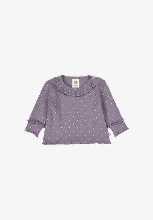 Maglietta viola a maniche lunghe con colletto arricciato, pois bianchi e polsi scallopati. Presenta un bottone laterale per facilitare la vestizione.