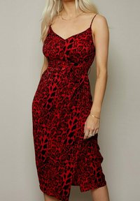 Rotes Kleid mit Leopardenmuster aus weichem Stoff, ausgestattet mit dünnen Trägern, einem taillierten Oberteil und einer gebundenen Taillendetail. Midilänge mit einem Schlitz.