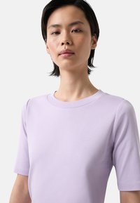 Lavender short-sleeve shirt made of soft fabric with a crew neckline. Smooth texture and fitted design. Simple, solid color without patterns.