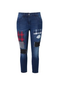 Jean en denim avec une finition bleu moyen, présentant des motifs de patchwork multicolores, des accents effilochés et des détails effilochés sur les jambes.