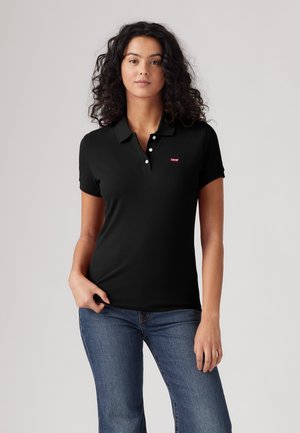 Zwarte poloshirt gemaakt van zacht materiaal, voorzien van een drukknoopsluiting met drie knopen, korte mouwen en een klein rood logo op de borst.