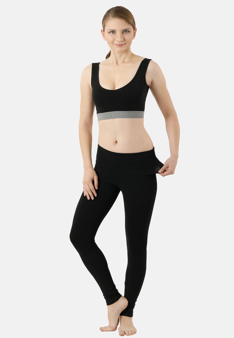 Black sports bra with a wide gray band under the bust; paired with black leggings featuring a foldable waistband and fitted design.
