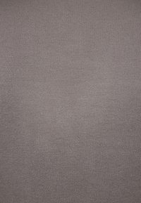 Tissu doux et côtelé de couleur grise douce, présentant une surface texturée avec des lignes verticales espacées régulièrement. Matériau léger et extensible.