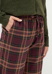 Kankaat harmaasta, ruskeasta ja mustasta. Valmistettu pehmeästä kankaasta, jossa on joustava vyötärö ja nauhavetoketju, ja siinä on sivutaskut.