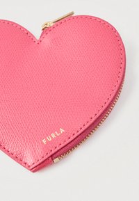 Srdcový ružový kožený peňaženka na mince s textúrovaným povrchom, zlatým zipsom a jemným vyrazeným logom značky na povrchu.
