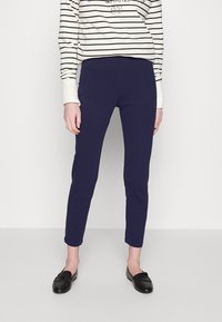 Marina stretchbyxor med en smal passform, mjuk textur och kort längd, kombinerat med en randig långärmad topp och svarta loafers.