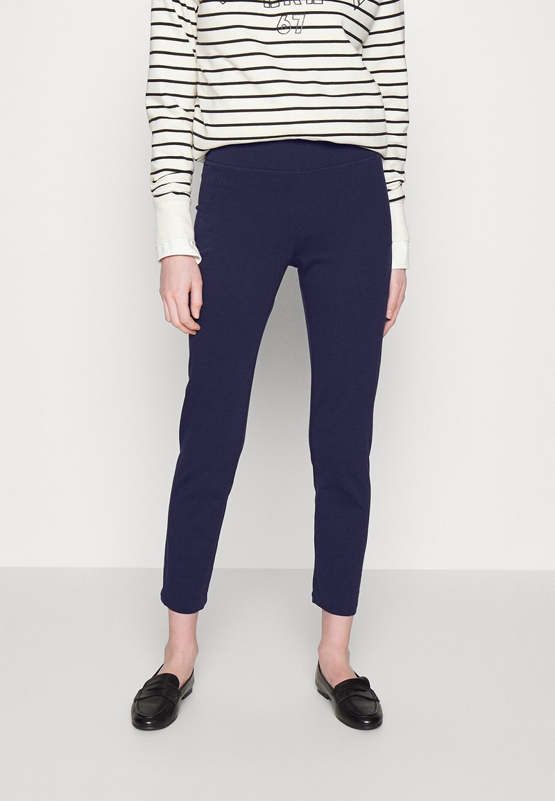 Marina stretchbyxor med en smal passform, mjuk textur och kort längd, kombinerat med en randig långärmad topp och svarta loafers.