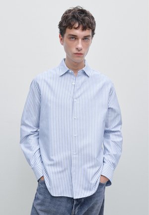 Blue and white striped button-up shirt, cotton fabric, classic collar, long sleeves, relaxed fit, featuring a curved hem and buttoned cuffs.