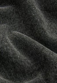 Tissu gris avec une texture à fines côtes, présentant de subtiles variations d'ombrage et de douceur, idéal pour les vêtements ou le tapissage.