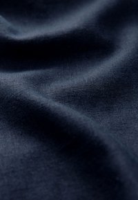 Mørkeblåt stof med en glat struktur, der har subtile farvevariationer og et let krøllet design.