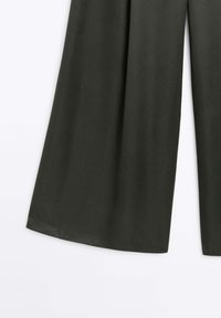 Szerokie spodnie wykonane z gładkiego, ciemnozielonego materiału, charakteryzujące się prostym, zwiewnym krojem, bez widocznych ozdób czy wzorów.
