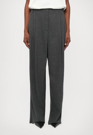 Grijze op maat gemaakte broek met een hoge taille, wijde pijpen en een gestructureerde stof. Heeft voorplooien en zwarte puntige schoenen.