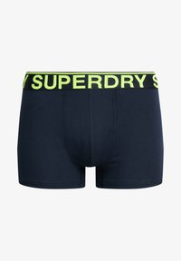 Calzoncillos boxer azul marino con un tejido suave, que presentan una cinturilla elástica de un llamativo amarillo neón con el texto "SUPERDRY".