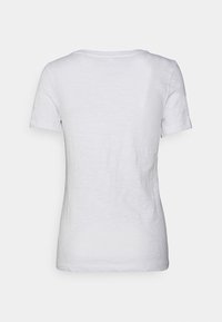 Camiseta blanca de cuello redondo y mangas cortas con una tela ligeramente texturizada, que presenta un diseño trasero simple y liso sin logotipos ni embellishments visibles.