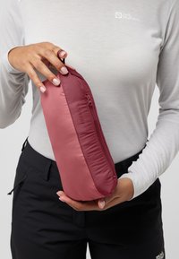 Pochette zippée rouge et rose tenue dans la main, avec une texture lisse, une forme arrondie et une petite boucle pour un transport facile.