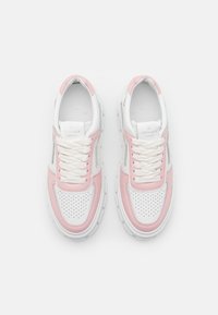 Weiße und pinke Sneakers mit einer strukturierten Oberseite, einem perforierten Zehenbereich und einer dicken Gummisohle. Die Schnürsenkel sind weiß und der Kragen hat eine leichte Polsterung.