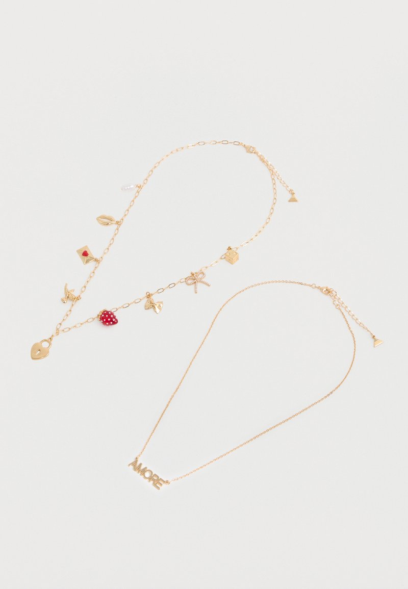 Deux colliers en ton or : l'un avec des breloques (cadenas, cœur, fraise, nœud), l'autre avec un pendentif texte "AMORE" sur des chaînes fines.
