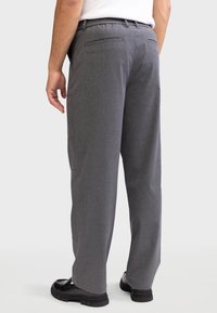 Gray trousers with a straight cut, made from textured fabric. Features include a waistband and two back pockets. Worn with black shoes.