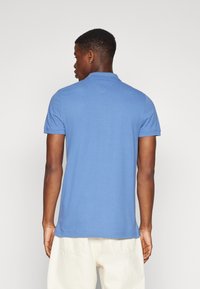 Camisa polo azul de algodón, con cuello clásico, mangas cortas y dobladillo recto. Textura suave con detalles de costura mínimos.