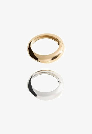 Kovové krúžky zo zlata a striebra, hladká textúra, zaoblený oválny tvar, leštený povrch. Dve odlišné farby na seba naskladané vertikálne.