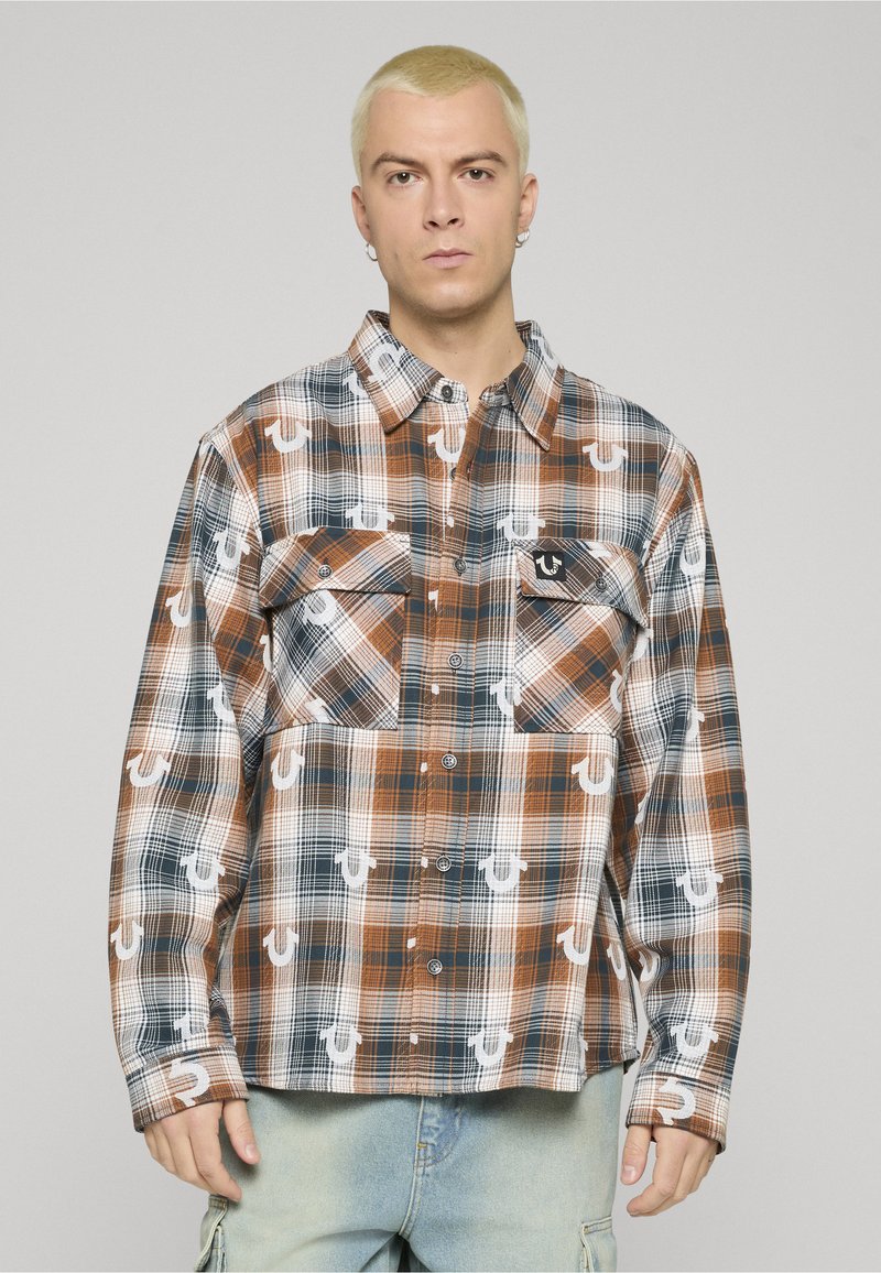 Camicia a quadri con bottoni in tonalità di marrone, blu e bianco, con due tasche sul petto e dettaglio con logo. Realizzata in tessuto leggero con vestibilità comoda.