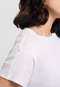 Biała koszulka T-shirt z krótkim rękawem, z fakturowanym ramieniem w pionowe linie oraz subtelnymi błyszczącymi akcentami. Gładka faktura materiału.