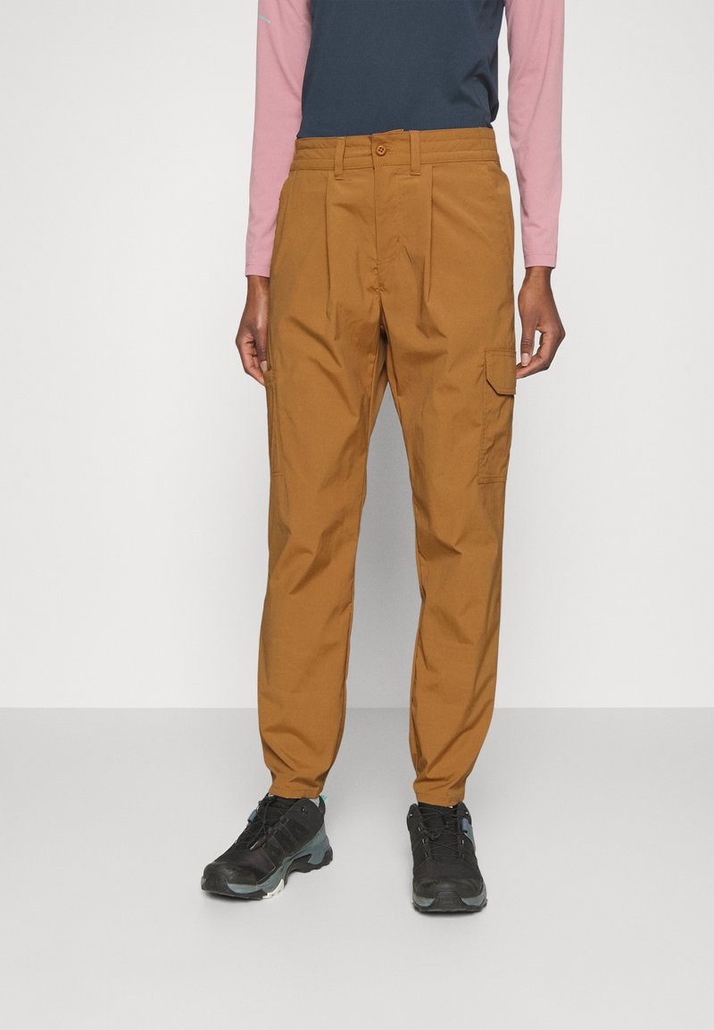Brown cargo trousers with a relaxed fit, featuring side pockets and a button closure, paired with black athletic shoes.