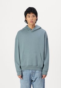 Felpa con cappuccio in teal tenue, in misto cotone, con un fit rilassato, tasca frontale, polsini e orlo ribattuti, caratterizzata da un design semplice e pulito.