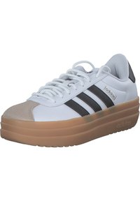 Białe sneakersy z gumową podeszwą, czarne trzy paski, zamszowy czubek i wyściółka dla komfortu. Logo "adidas" z boku.