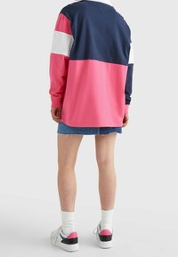 Langärmliges Oberteil mit Farbblöcken in Marineblau, Weiß und Rosa; lässiges Design mit lockerer Passform und Baumwollmaterial, kombiniert mit Jeansshorts.