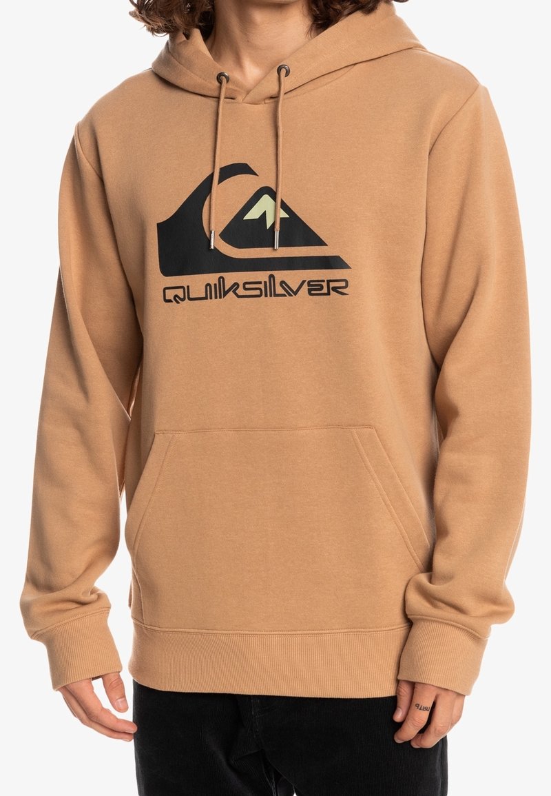 Felpa marrone con tasca a marsupio frontale, cappuccio con cordino e logo Quiksilver nero con grafica di una montagna verde. Tessuto morbido.
