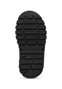 Svart gummisul med djupa mönster för grepp, med upphöjda prickar och linjer. "NATURINO"-logotypen är präglad på ytan.