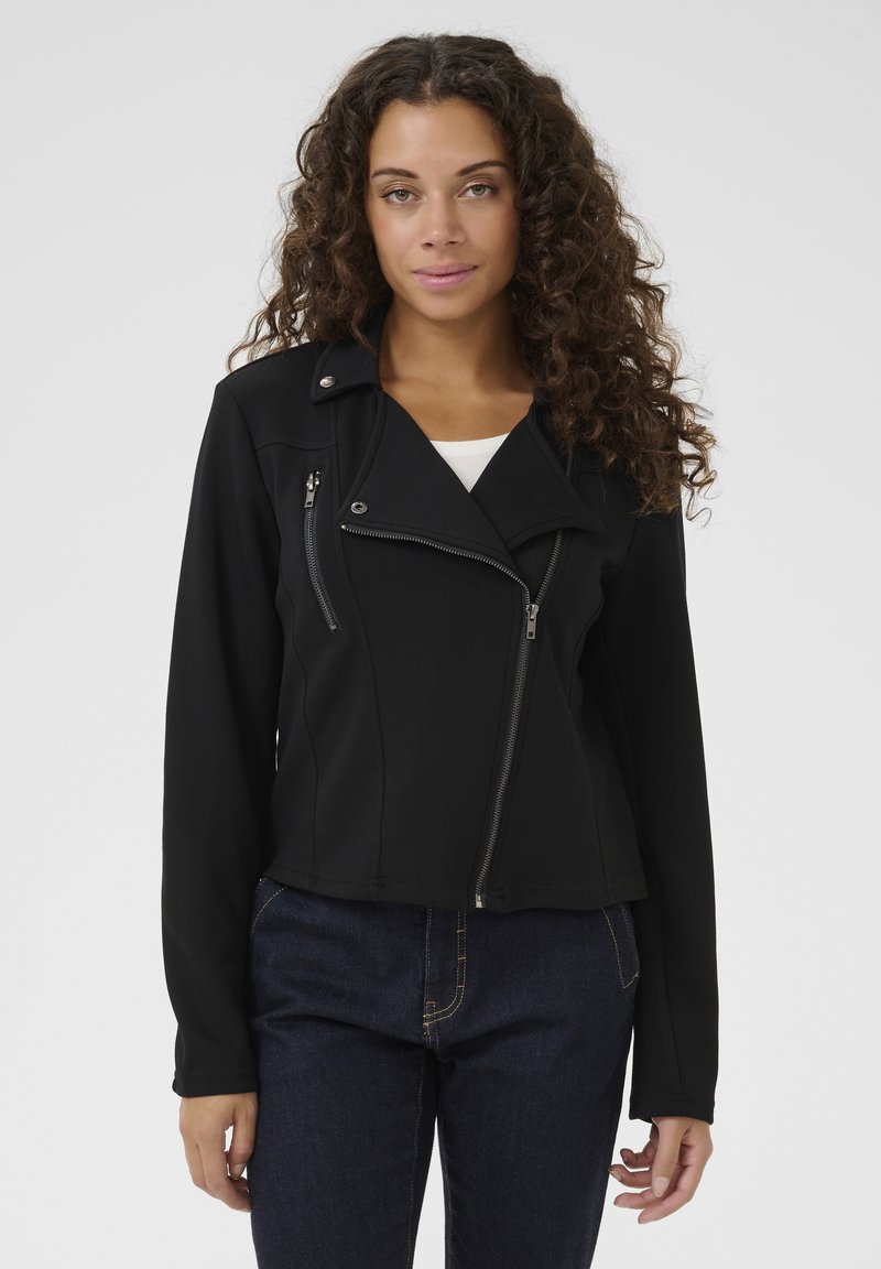 Svart motorcykeljacka med en figurnära design, dragkedjefickor och asymmetrisk framdragkedja. Tillverkad av ett slätt tyg med en strukturerad look.