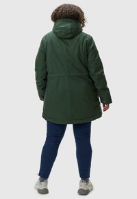 Žalias vandeniui atsparus parka su gobtuvu, užbaigtas lygia tekstūra ir šiek tiek laisvu siluetu. Turi snap-button akcentus ir apytiksliai iki šlaunų ilgį.