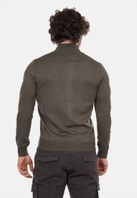 Maglione a maglia verde oliva con una texture a coste e un design aderente, con colletto rotondo e maniche lunghe.