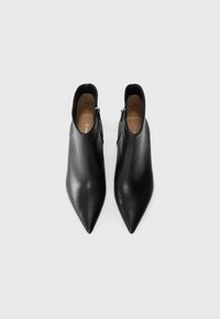Pair of black leather pointed-toe ankle boots with side zippers, shown from above on a light gray background.