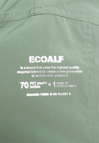 Logo i tekst ECOALF na zielonym materiale informujący, że 70 butelek PET równa się 1 metrowi materiału z recyklingu ECOALF, promując przesłanie o zrównoważonym rozwoju.