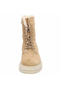 Bota de tobillo de ante marrón con forro de borreguito, puntera redonda y cordones marrones. Suela gruesa y texturizada que proporciona tracción y soporte adicional.