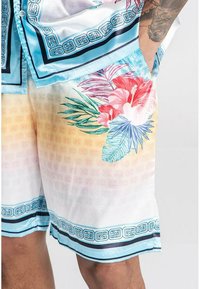 Satin shorts med et tropisk blomstermønster i pink og grøn, med en gradient fra hvid til lys orange og blå accenter.