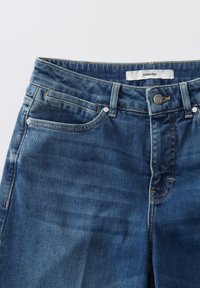 Jean en denim de couleur bleu foncé, avec un design classique à cinq poches, fermeture à bouton en métal et dégradé subtil. L'étiquette indique "un jour".
