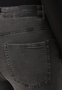 Σκούρο τζην παντελόνι με στενή εφαρμογή, που διαθέτει πίσω τσέπη και ετικέτα που γράφει "τέλεια τζην" από τη Gina Tricot κοντά στη μέση.