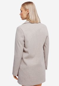 Lichtgrijze wollen blendjas met een gestructureerde silhouet, voorzien van een notch-kraag en strakke lijnen, getoond vanuit de achterkant.